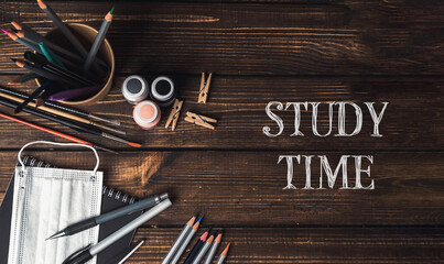 A wooden table with a bowl of pencils, a bottle, and a pair of scissors