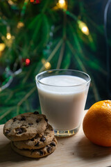 Glass of milk and cookies by a lit Christmas tree and Bright orange tangerines