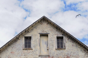 Historic prison with barred windows, weathered door, blue sky, and seagull.