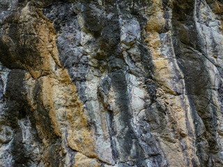Amazing hillside cliff with compressed layer rock structure of volcanic rock. Close-up texture of volcanic rock. Cracked broken crumbled.
