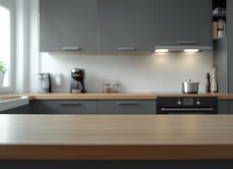 A wooden countertop in a modern kitchen with gray cabinets, a stainless steel sink, and a window with a plant.
