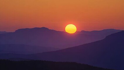 Fototapeta premium Serene Sunset Over Mountains with Glowing Sun and Vibrant Sky