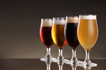 Glasses with different types of beer on mirror surface, closeup. Space for text