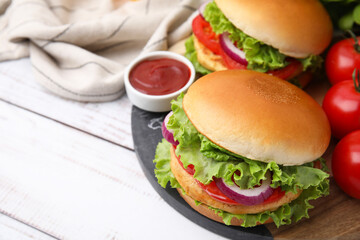 Delicious vegetarian burgers with chickpea cutlets, tomatoes and sauce on white wooden table, closeup. Space for text