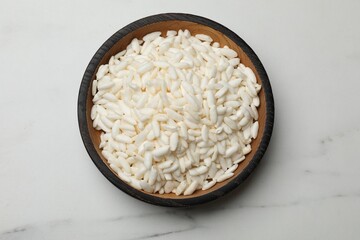 Puffed rice in bowl on white marble table, top view