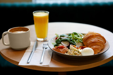 Tasty breakfast. Freshly baked croissant and salad served on wooden table in cafe