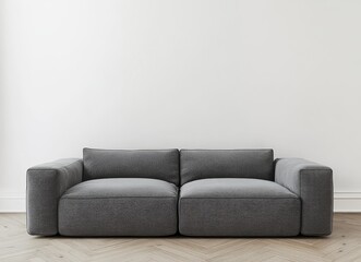 A gray sofa in a minimalist living room with a white wall and herringbone wooden floors.