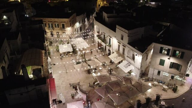 Vis&atilde;o a&eacute;rea deslumbrante da cidade hist&oacute;rica de Ostuni, It&aacute;lia, destacando suas ruas estreitas, casas brancas e o cen&aacute;rio pitoresco ao fundo, com vista para a paisagem mediterr&acirc;nea
