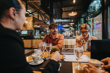 A group of business people engage in a meeting at a contemporary cafe, discussing projects over coffee. The atmosphere is collaborative and dynamic, emphasizing teamwork and productivity.