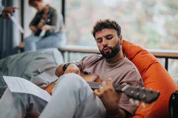 A student plays guitar during a college music class, enjoying a creative and interactive learning environment with peers.