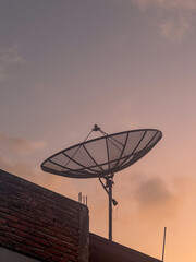 Satellite dish on the roof at sunset