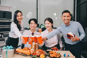 full length view of a group of business team wearing red Santa hat and exchange gift box together in the office for Christmas.