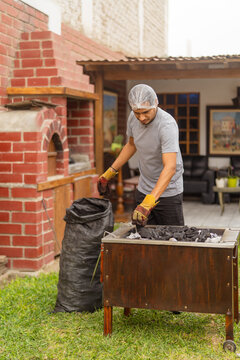 Cook preparing charcoal grill in garden for barbecue party