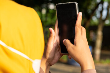 A person is deeply engrossed in their smartphone, their fingers scrolling through the screen. The...