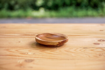 Selective focus. Wood grain end table with round wood base on blur green forest background for montage product display or design