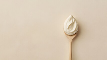 Creamy white substance on a wooden spoon against a soft beige background, perfect for culinary and food-related imagery and concepts of freshness and texture