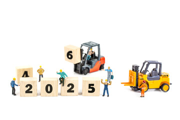 Fototapeta premium miniature worker team building standing front of forklift machine with 2025 number on wooden block on white background, decoration to Happy new year 2025 concept.