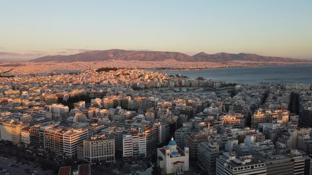 Vis&atilde;o a&eacute;rea do p&ocirc;r do sol no centro urbano de Atenas, Gr&eacute;cia, com tons dourados iluminando a cidade hist&oacute;rica e seus monumentos ic&ocirc;nicos