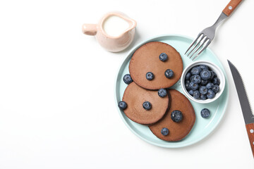 Chocolate pancakes on plate, bowl with berries, cutleries and jug on white background, space for text