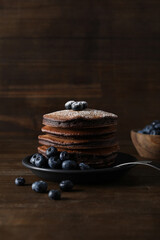 Chocolate pancakes and berries on plate on wooden background