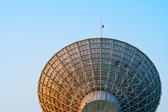 Radio telescope giant paraboloid surface in morning sunlight with blue sky background