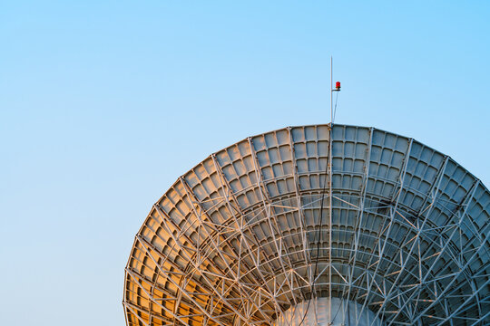 Radio telescope giant paraboloid surface in morning sunlight with blue sky background