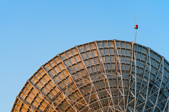 Radio telescope giant paraboloid surface in morning sunlight with blue sky background