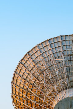 Radio telescope giant paraboloid surface in morning sunlight with blue sky background