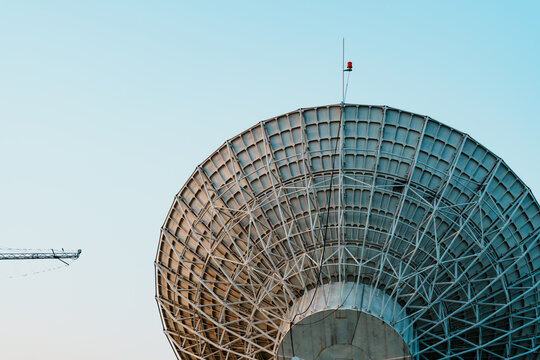 Radio telescope giant paraboloid surface in morning sunlight with blue sky background
