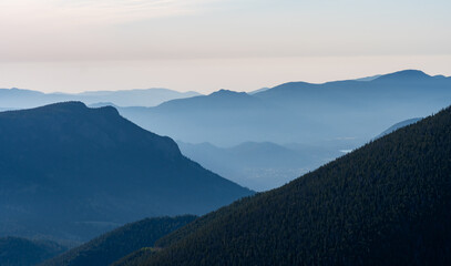 Layers of misty mountains stretch across the horizon during dawn, showcasing a serene landscape in the quiet of early morning