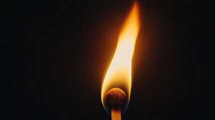Bright orange flame of a burning match, close-up, glowing vividly against a deep black background.