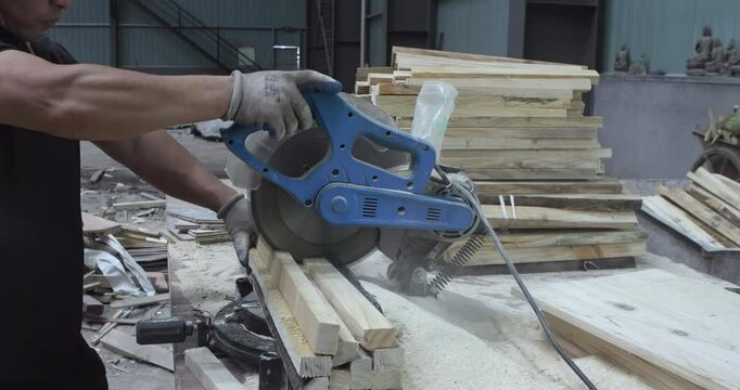 A man is cutting a piece of wooden plank with circular saw