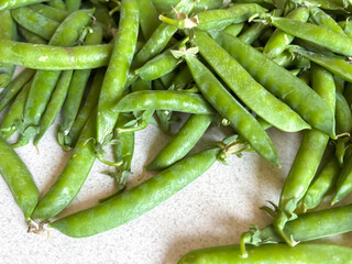 Lots of green peas in pods. Green peas on a light background. Pea pods are the season of vitamins.