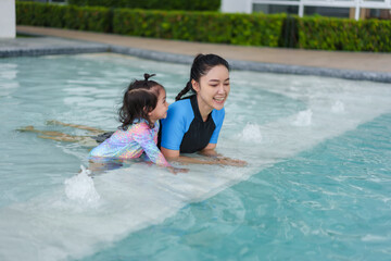 happy mother with toddler baby girl in edge of swimming pool