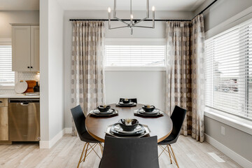 A dining room with a table and chairs, and a chandelier above the table