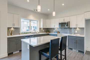 A kitchen with a white island and black chairs
