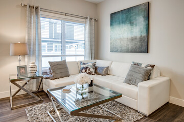 A white couch and coffee table with a blue painting on the wall