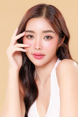 Pretty Asian beauty woman curly long hair with Korean makeup glowing face and healthy facial skin portrait smile on isolated beige background. Cosmetology ,Plastic surgery.