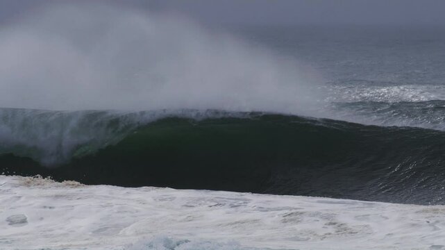 Huge wave forms a perfect barrel, mist drifting off as it crashes forward