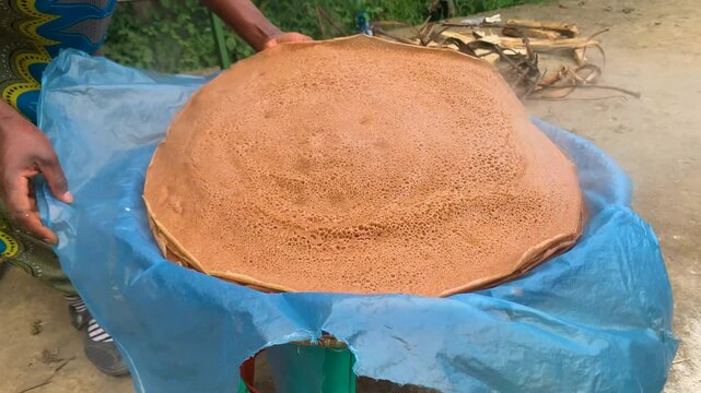 Ethiopian maid girl arranging injera after finish cooking piling hot enjira