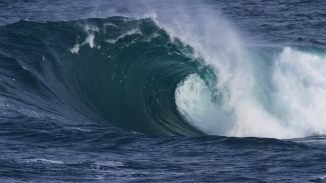Large wave barrels, foam ball spraying out from the curl in powerful, slow motion detail