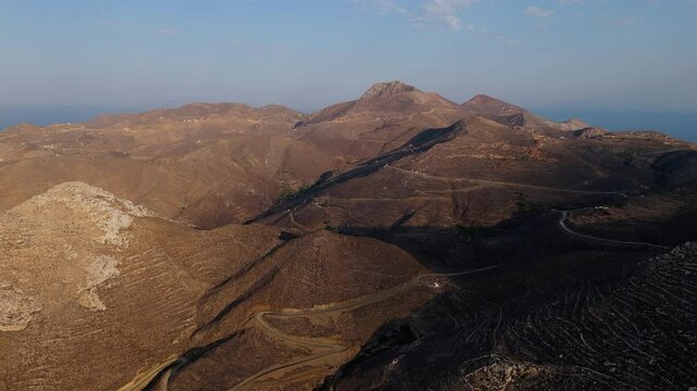Aerial high angle overview of Anafi rugged coast, calm evening light over cliffs and scenic island view