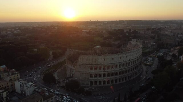 Vis&atilde;o a&eacute;rea do Coliseu de Roma ao final do dia, com o sol se pondo no horizonte. O v&iacute;deo destaca a beleza do monumento hist&oacute;rico iluminado pelas &uacute;ltimas luzes do dia, com a cidade ao fundo
