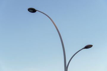 metal streetlight with two isolated lights on a clean blue sky