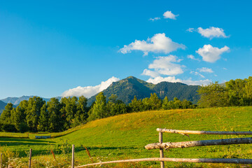 Landscape of the rural area with meadow and wooden fence and mountains