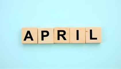 APRIL month sign on wooden cubes with blue background.