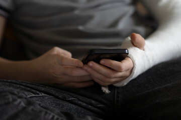 A child with an arm in a cast uses a phone
