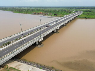 Aerial photograph showing a highway bridge spanning a wide river, surrounded by lush green...