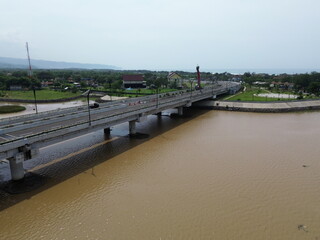 Aerial photograph showing a highway bridge spanning a wide river, surrounded by lush green...
