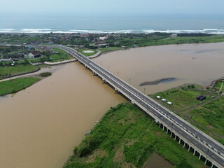 Aerial photograph showing a highway bridge spanning a wide river, surrounded by lush green...